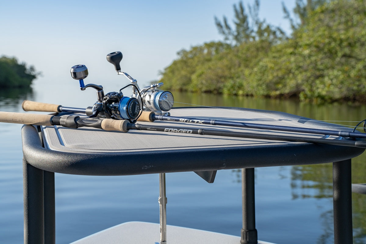 Fishing rods and reels on a pontoon with a lake and trees in the background