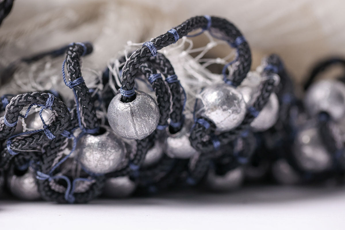 Close-up of black and blue braided cord with silver beads on a white background