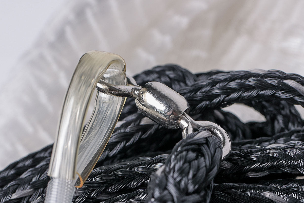 Close-up of a metal carabiner attached to black rope with a blurred background