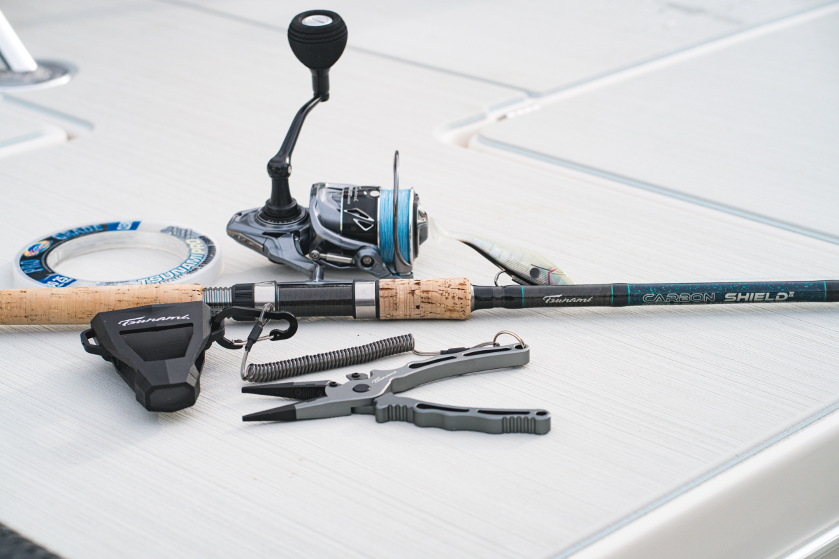 Fishing rod, reel, and pliers on a white tiled surface