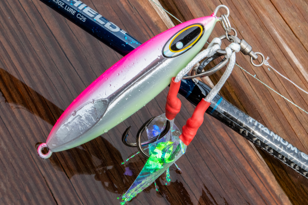 Fishing lure with a pink and green body on a wooden surface
