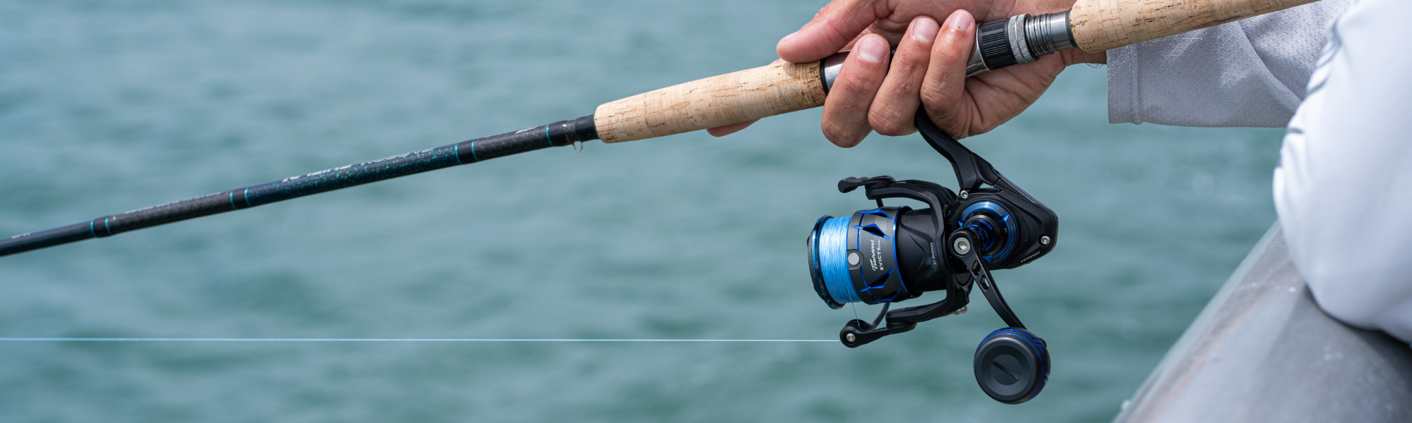 A fisherman, who is fishing from a pier, is using a Tsunami Carbon Shield III and Tsunami Evict II rod and reel combo