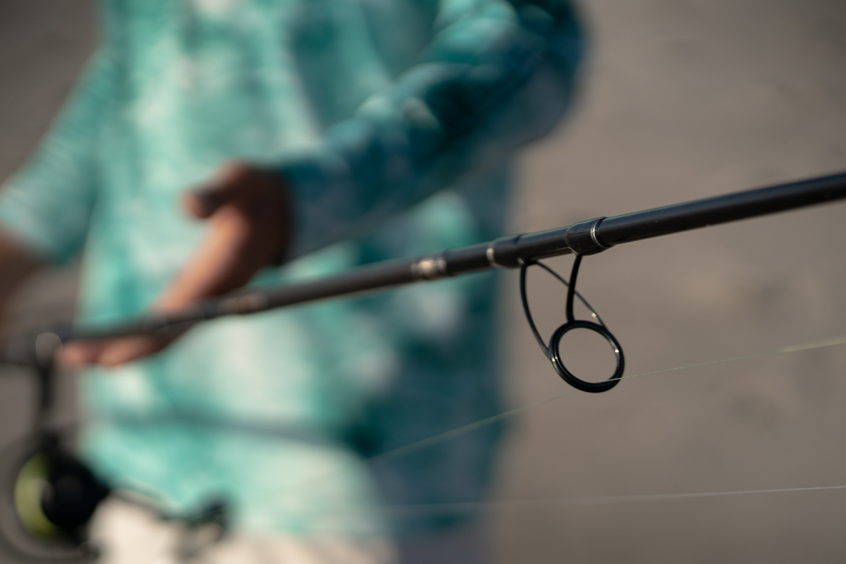Fishing rod held by a person wearing a teal shirt with a blurred background