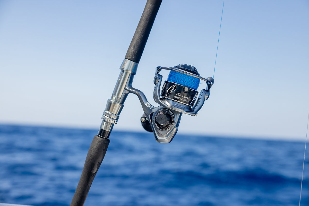 Fishing rod with reel against a blue sky and ocean background