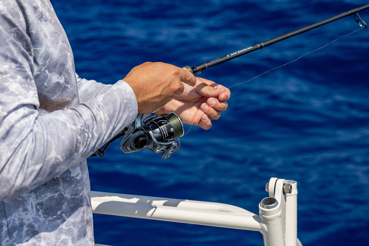 Person fishing with a rod on a boat against a blue water background